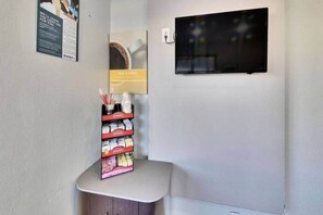 A corner of a room with a small table holding a stack of books and a framed picture on the wall.