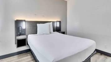 Habitación de hotel moderna con una cama grande, dos mesitas de noche e iluminación en la pared.