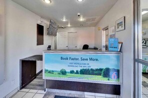 A reception desk with a sign advertising a booking app, a door, and a security camera.