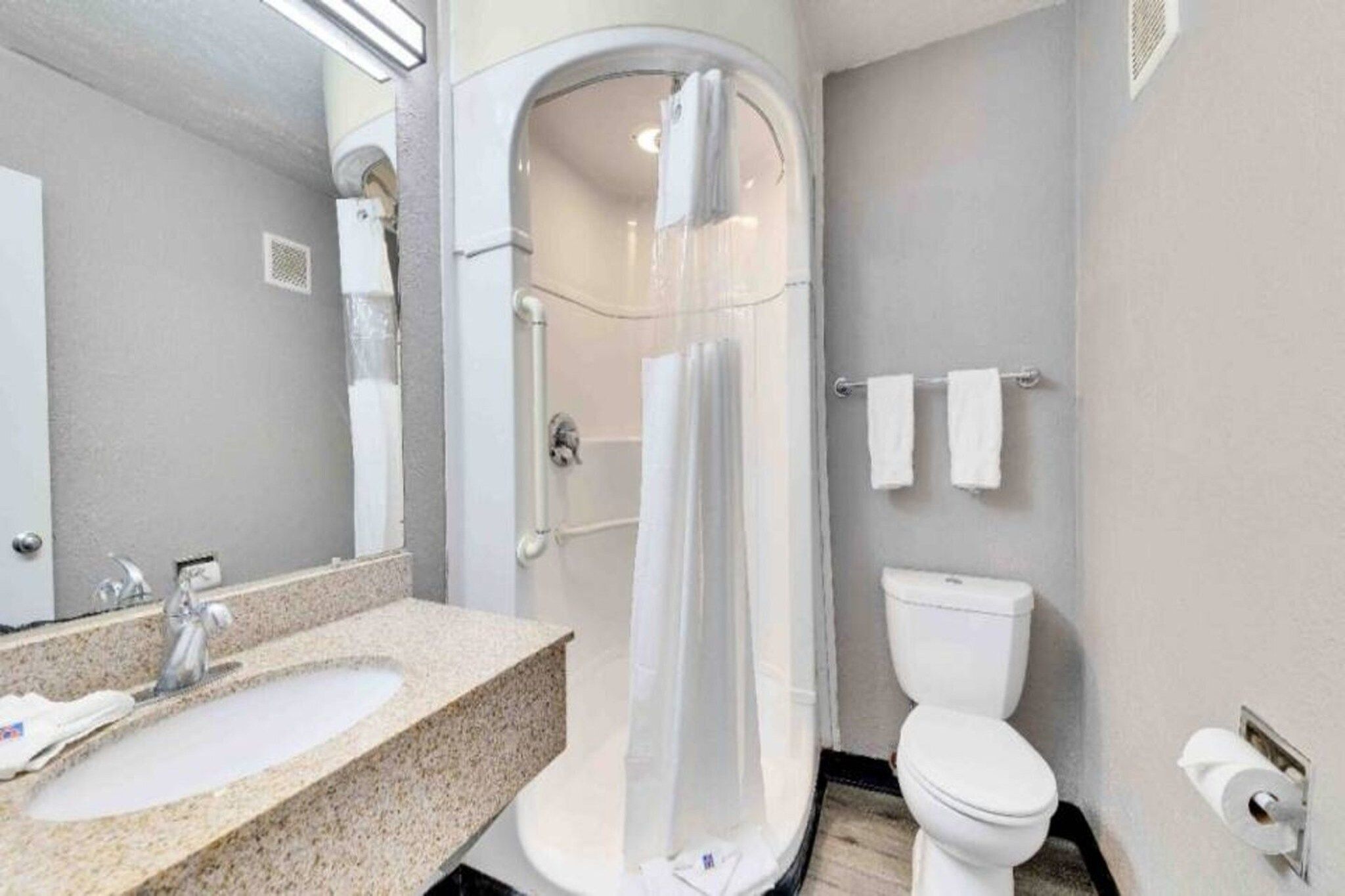 A bathroom with a shower enclosure, a sink, a toilet, and a towel rack.