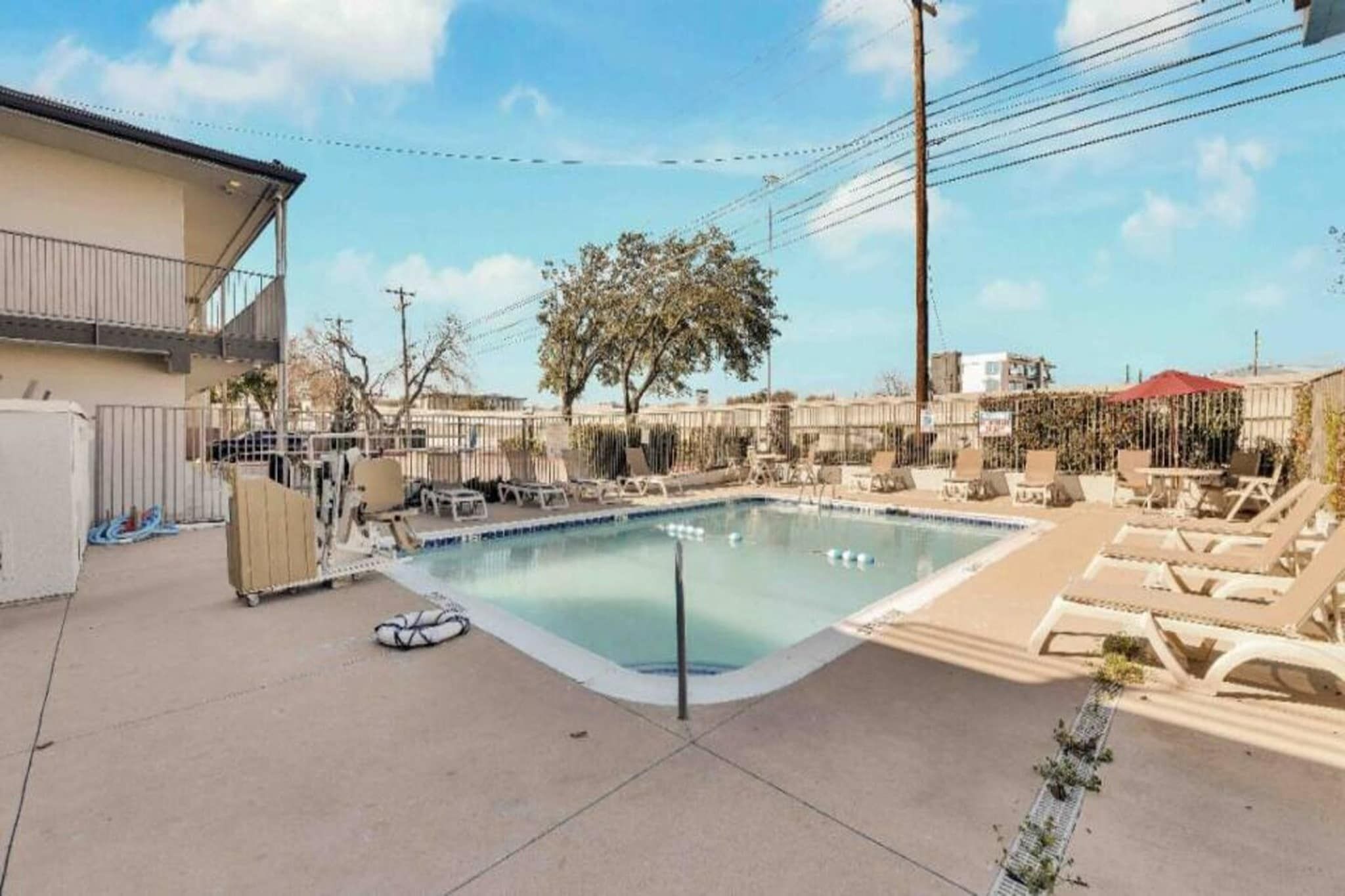 A swimming pool with lounge chairs and a tree in the background.