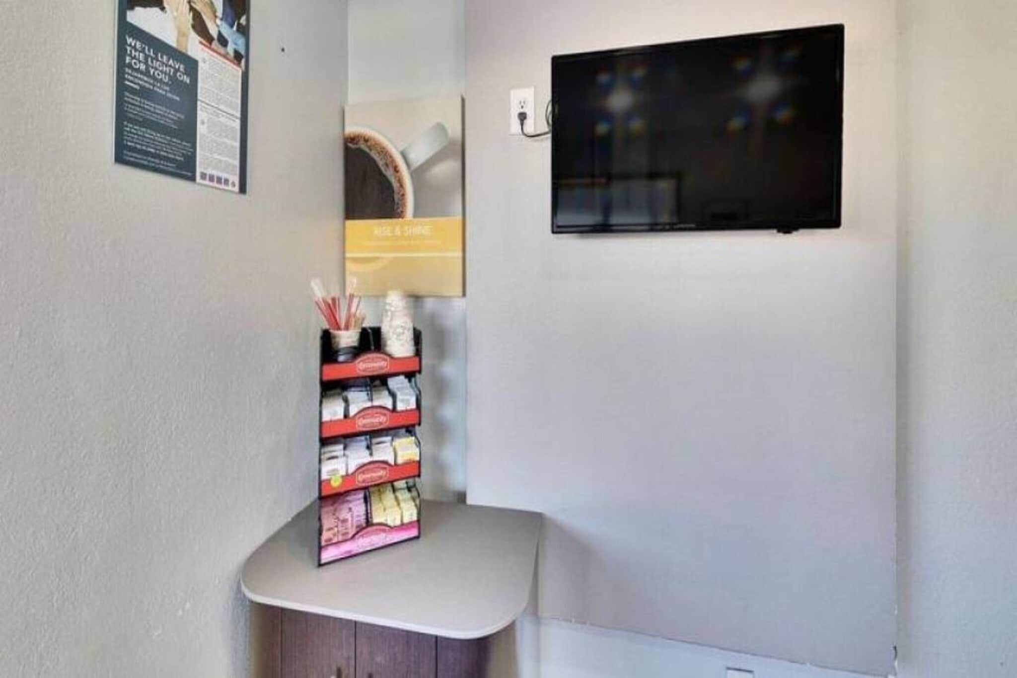 A corner of a room with a small table holding a stack of books and a framed picture on the wall.