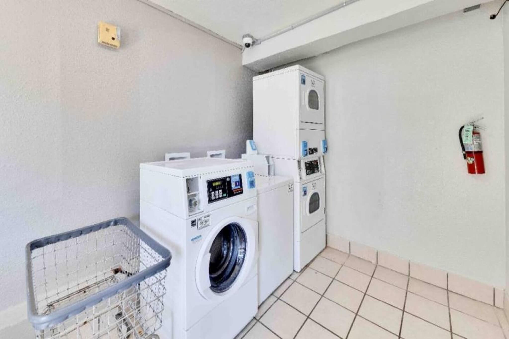 A laundry room with a washing machine, dryer, and a fire extinguisher on the wall.