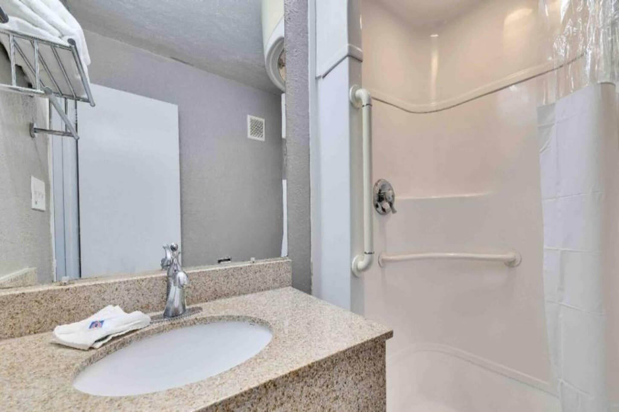 A bathroom with a sink, mirror, and shower.