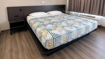 A hotel room with a bed, a nightstand, a heater, and a window with curtains.