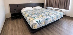 Ein Hotelzimmer mit Bett, Nachttisch, Heizung und einem Fenster mit Vorhängen.