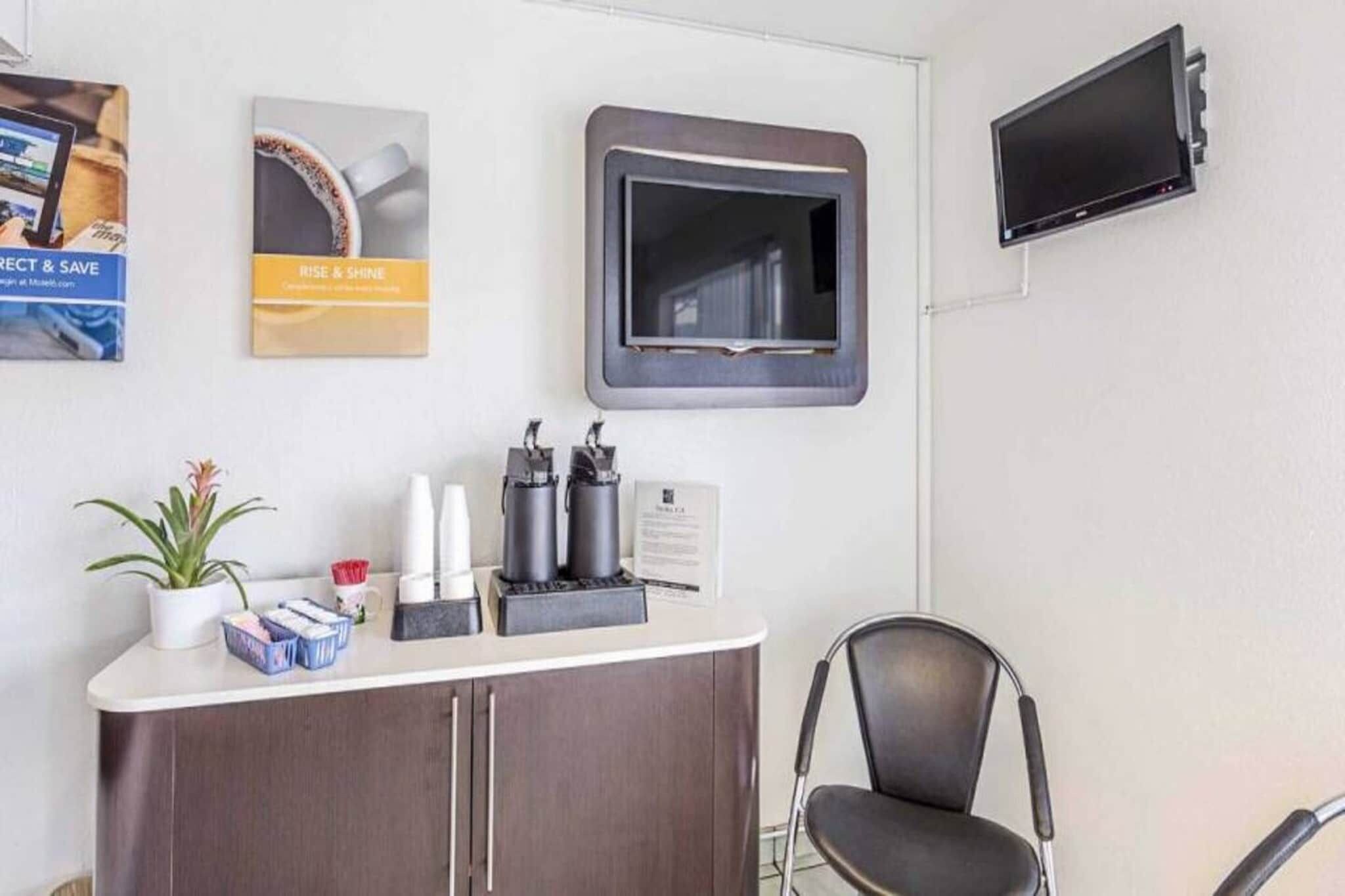 A reception area with a counter, a chair, a television, and some wall decorations.