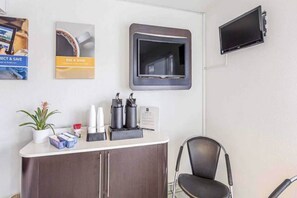A reception area with a counter, a chair, a television, and some wall decorations.
