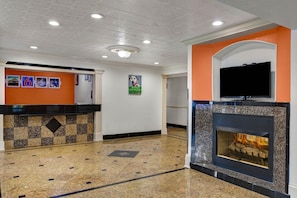 Eine Lobby mit einer Rezeption, einem Kamin und einem Fernseher.
