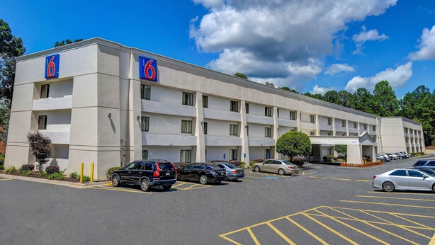 A motel with a parking lot, multiple cars, and a clear blue sky. - 1 King Bed | Non-Smoking (Norcross)