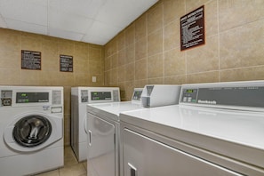 A laundry facility with multiple machines, including a front-loading washer and a top-loading dryer, and clear instructions on the wall. - 1 King Bed | Smoking (Norcross)