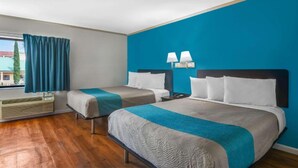 Hotellihuone, jossa on kaksi sänkyä, ikkuna, jossa on verhot, lamppu ja lämmitin.