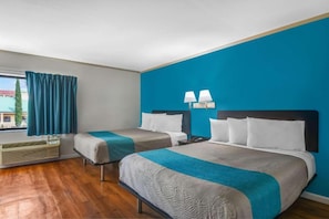 Ein Hotelzimmer mit zwei Betten, einem fensterbelaubten Fenster, einer Lampe und einem Heizgerät.