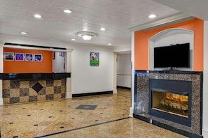 Eine Hotelhalle mit einer Rezeption, einem Kamin und einem Fernseher.