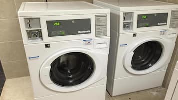 Two white front-loading washing machines with digital displays, placed in a tiled area.