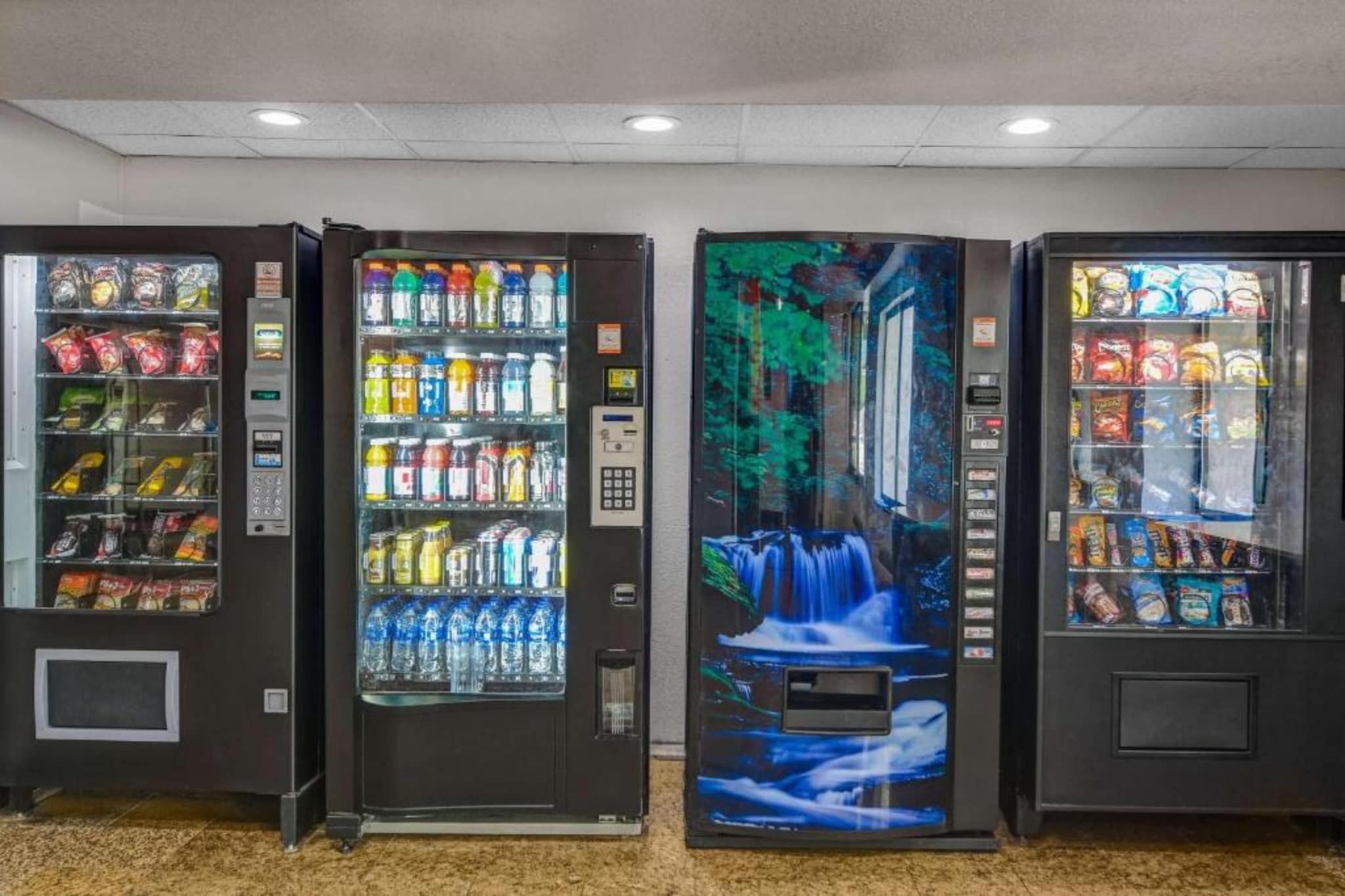 Three vending machines with various beverages and snacks.