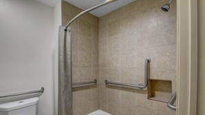 A bathroom with a shower, toilet, and grab bars. - 1 King Bed|Mobility|Tub|Smk (Norcross)