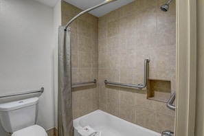 A bathroom with a shower, toilet, and grab bars. - 1 King Bed|Mobility|Tub|Smk (Norcross)