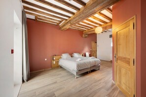 Une chambre avec un plafond en bois, un lit avec une literie blanche et une porte en bois.