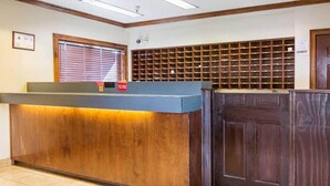 Uma receção com bancada de madeira, chão em azulejos e janela com estores.