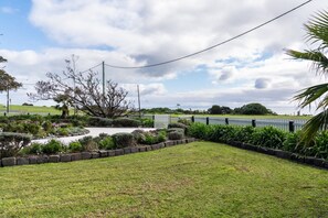 A landscaped garden with a curved pathway, a variety of plants, and a white fence.