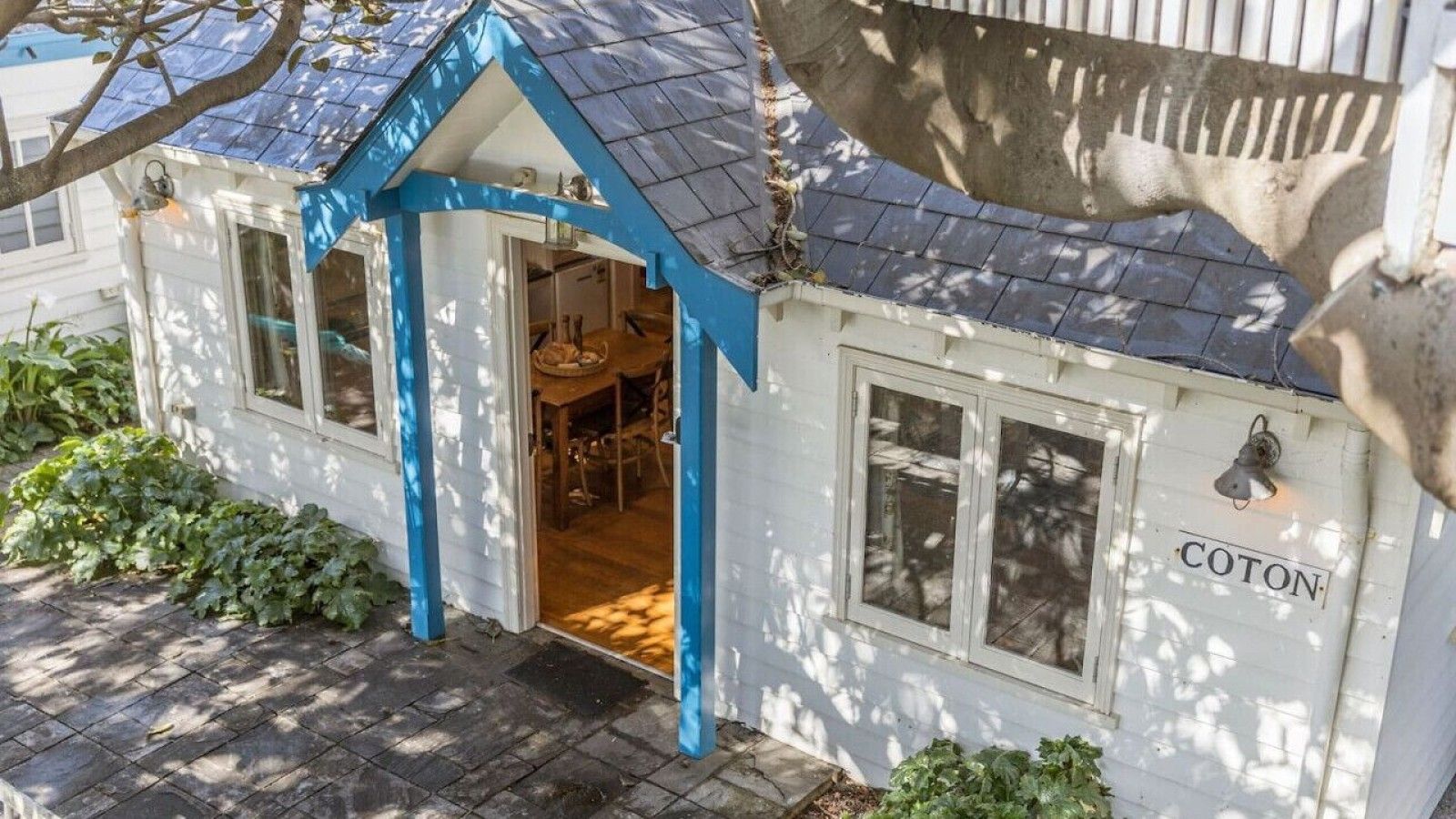 A small building with a blue roof and a door leading inside. The name 'COTON' is visible on the side.