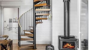 A modern interior with a spiral staircase, a wood-burning stove, and a white-tiled wall. - Beachfront Cottage - COTON COTTAGE - Sleeps 6! (Portarlington)