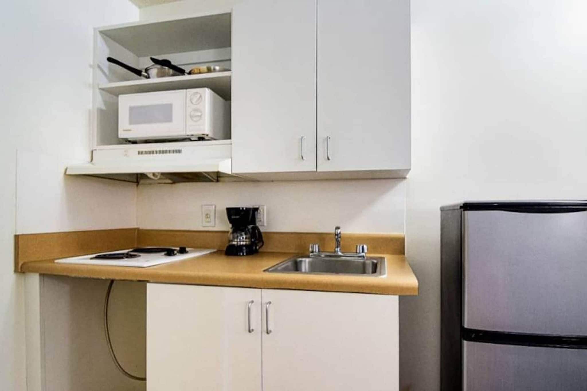 A compact kitchenette with a microwave, a coffee maker, and a sink.