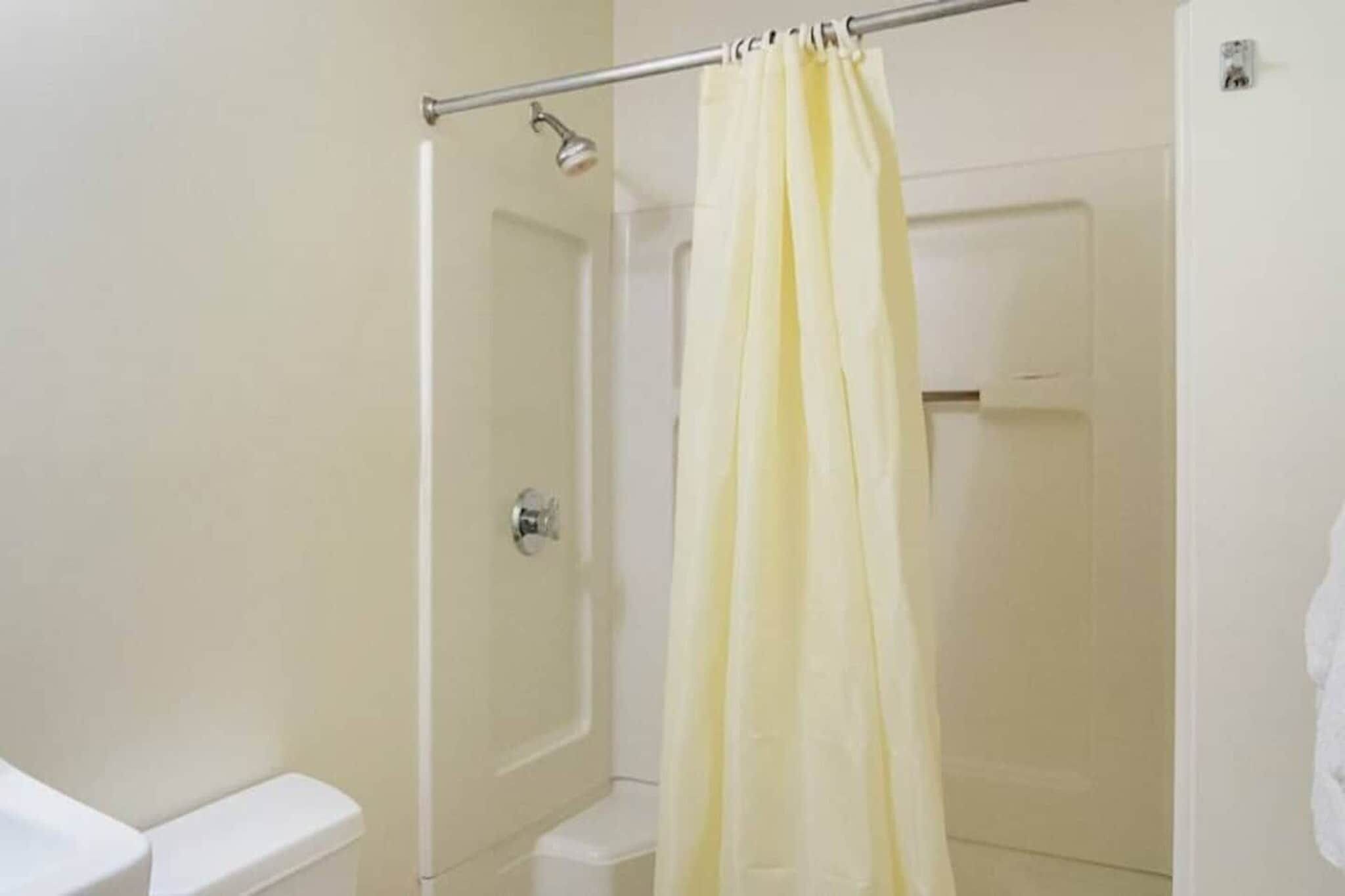 Een badkamer met een douche, toilet en een deur.