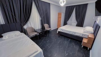A hotel room with two beds, a desk, and a chair.
