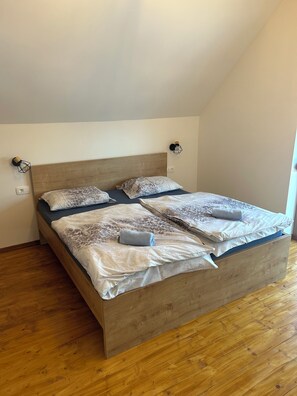 A single-bed room with a wooden headboard, a bedside table, and a wall-mounted light fixture. - Cozy 2-bedroom house in charming Gradišča with AC and Sauna (Cirkulane)