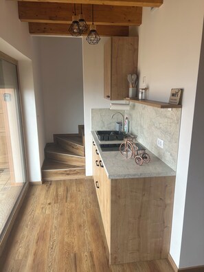 A modern kitchen with wooden cabinetry, a marble countertop, and a bicycle. - Cozy 2-bedroom house in charming Gradišča with AC and Sauna (Cirkulane)