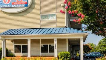 A motel with a blue roof, a porch, and a sign indicating extended stay availability.
