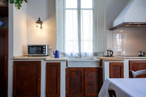 A kitchen with wooden cabinets, a microwave, a kettle, and a sink. - B&G Corte Menconi Iris (Orentano)
