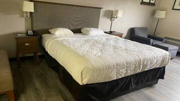 A hotel room with a large bed, two bedside tables, a chair, and a desk.