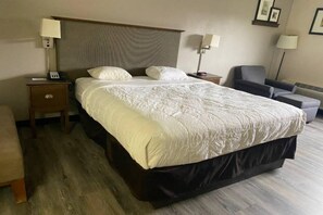 Ein Hotelzimmer mit einem großen Bett, zwei Nachttischen, einem Sessel und einem Schreibtisch.