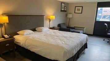 Een hotelkamer met een groot bed, bedlampen, een stoel en een bureau met een telefoon.