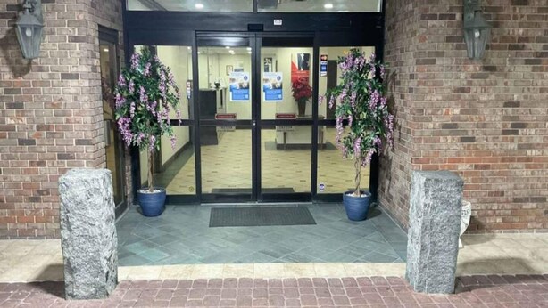 A hotel entrance with a brick facade, double doors, and two potted plants on either side. - 1 King Bed|Smoking| Kitchen (Columbus GA)