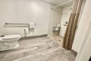 A bathroom with a toilet, a handrail, a towel rack, and a shower curtain. - 1 King Bed|Smoking| Kitchen (Columbus GA)