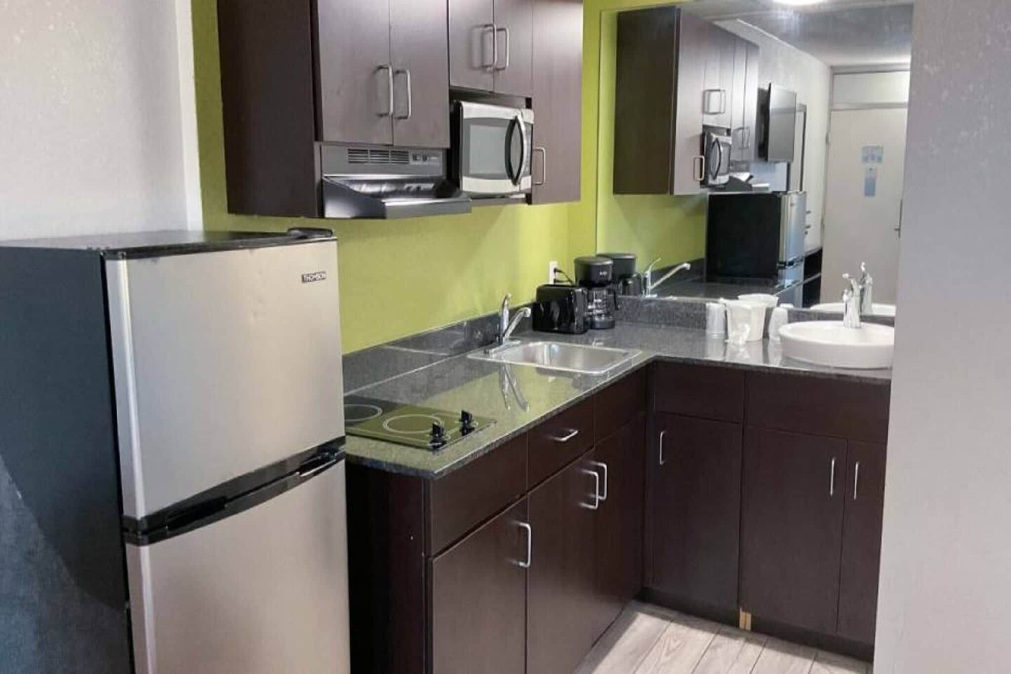 A compact kitchen with a refrigerator, microwave, stove, sink, and cabinets.