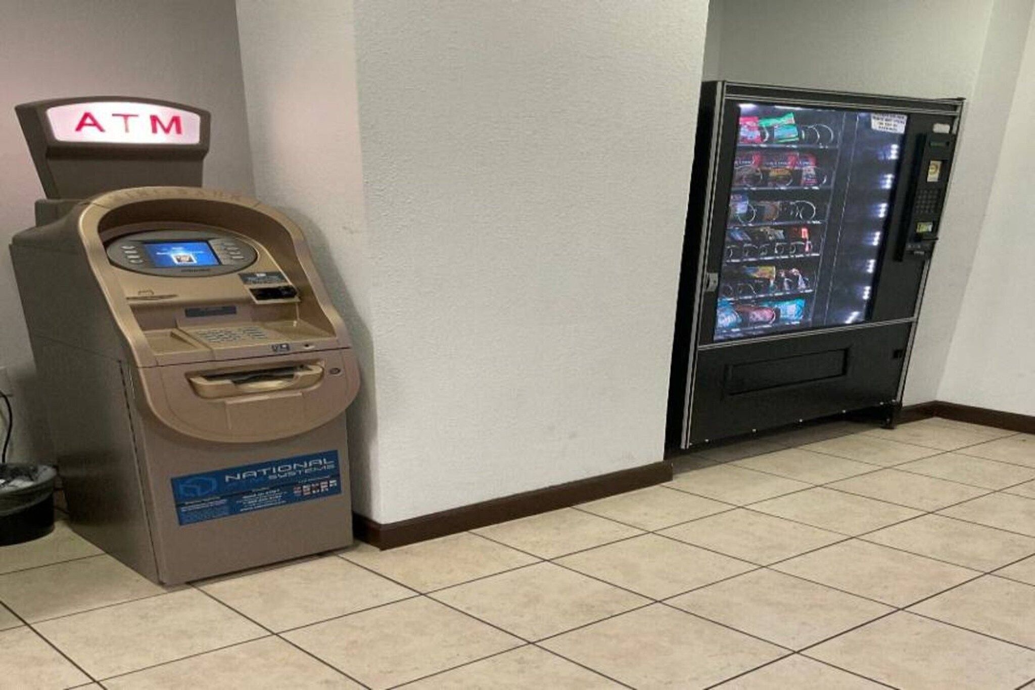 An ATM and a vending machine in a hallway.