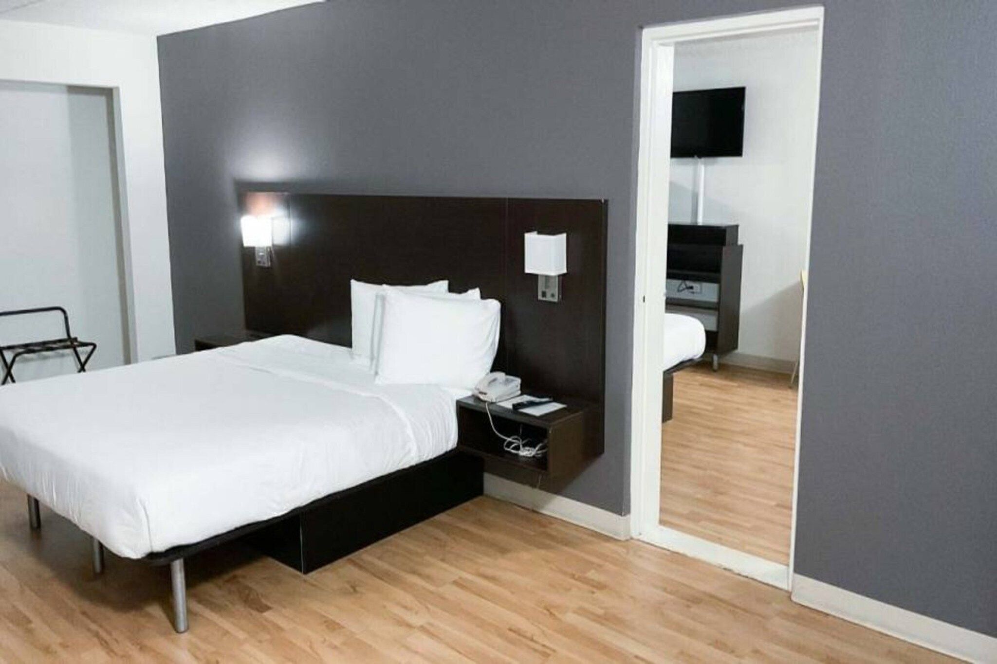 A hotel room with a bed, bedside table, and a mirror.