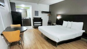 A hotel room with a bed, a desk, and a chair. - 1 King Bed Non-Smoking Kitchen (Columbus GA)