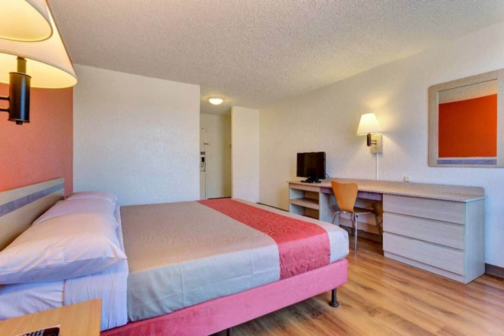 Ein Hotelzimmer mit Bett, Schreibtisch, Stuhl und Fernseher.