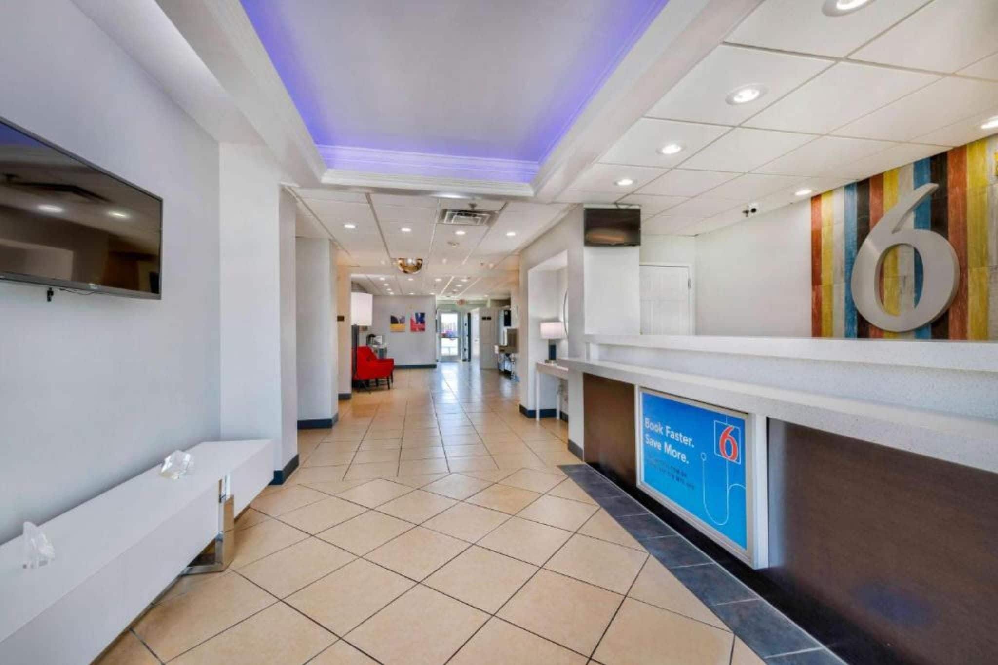 Un hall d'accueil d'hôtel avec un sol carrelé, un comptoir de réception et un grand panneau portant le chiffre « 6 ».