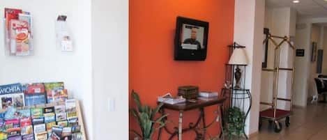 Una zona de recepción con un mostrador, una foto enmarco, una lámpara de pared y un carrito.