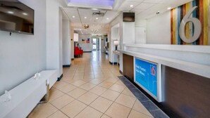 A hotel reception area with a tiled floor, a reception desk, a TV mounted on the wall, and a colorful wall decoration. - 2 Full Beds | Non-Smoking, Micfridge (Norman)