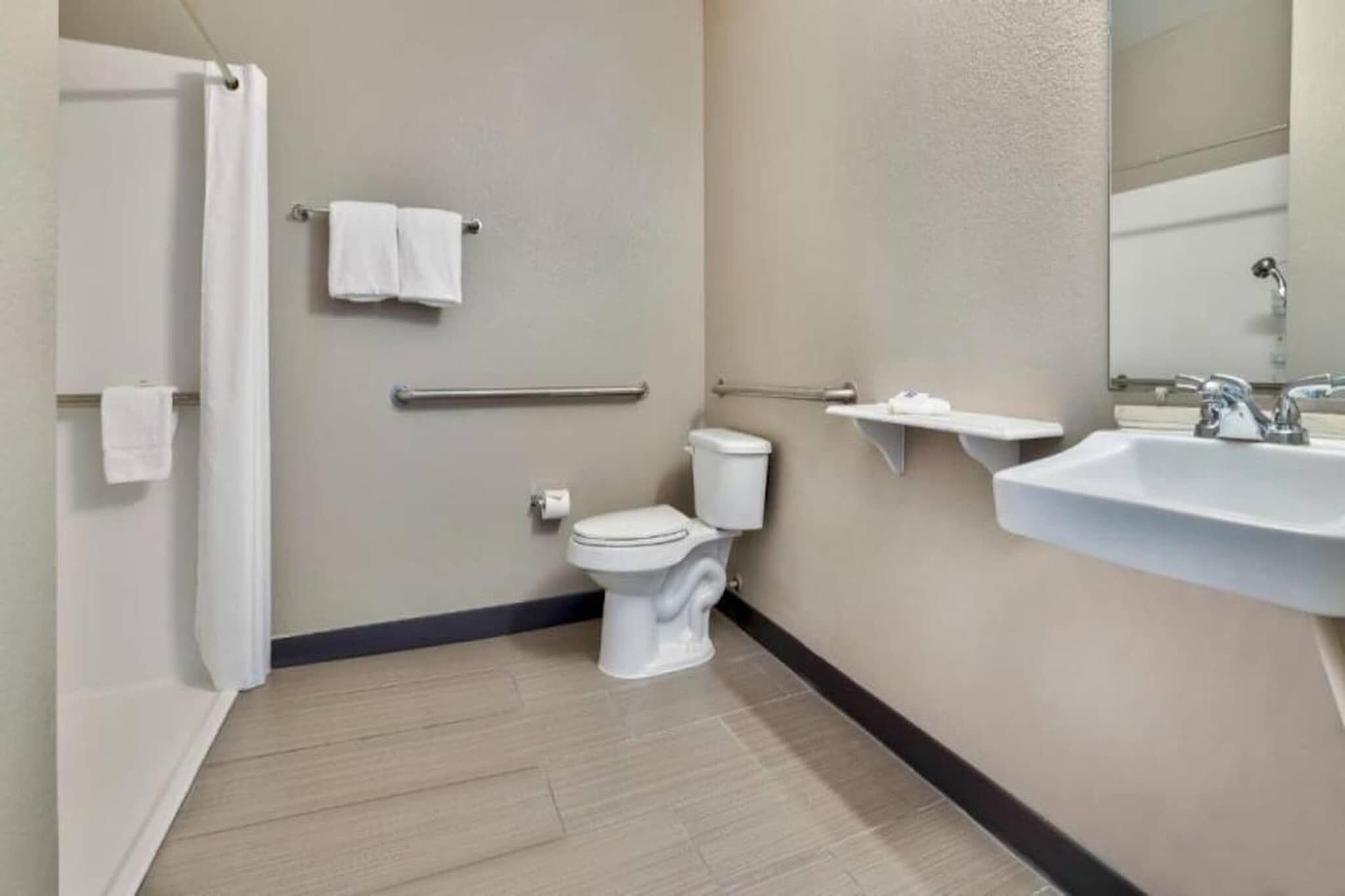 A bathroom with a toilet, a sink, a towel rack, and a shower curtain.