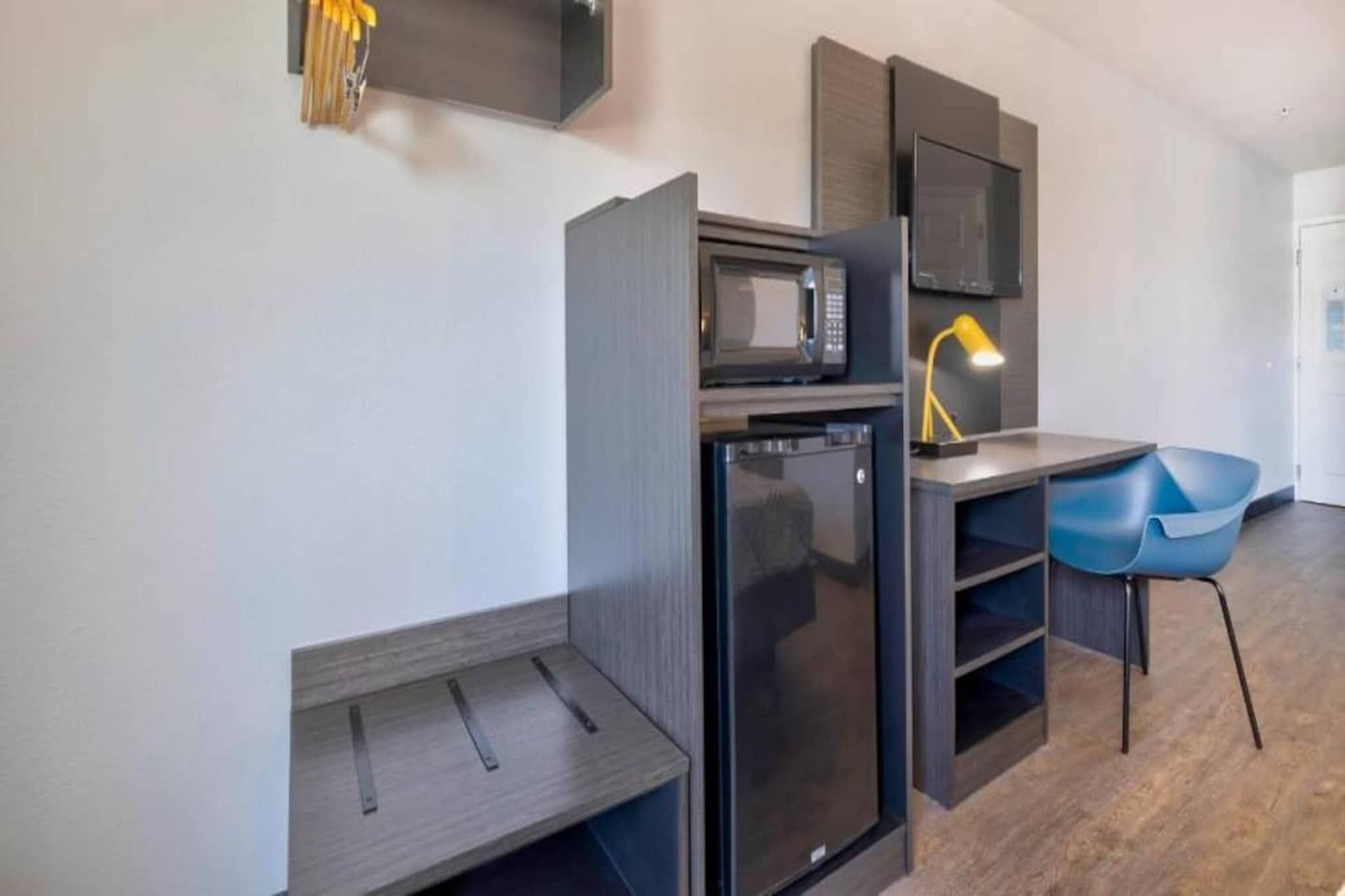 A compact kitchenette with a microwave, refrigerator, and a small table with a chair.