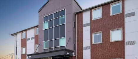 Un hotel de varios pisos con un llamativo letrero con el número '6', amplias ventanas y fachada de ladrillo.